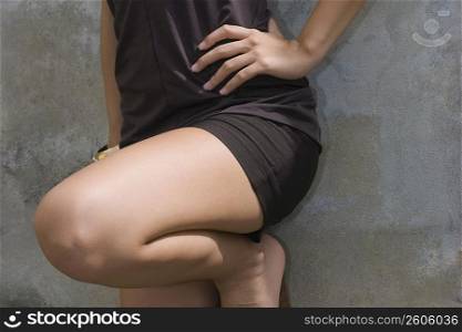 Close-up of a woman leaning against a wall with her hand on her hip