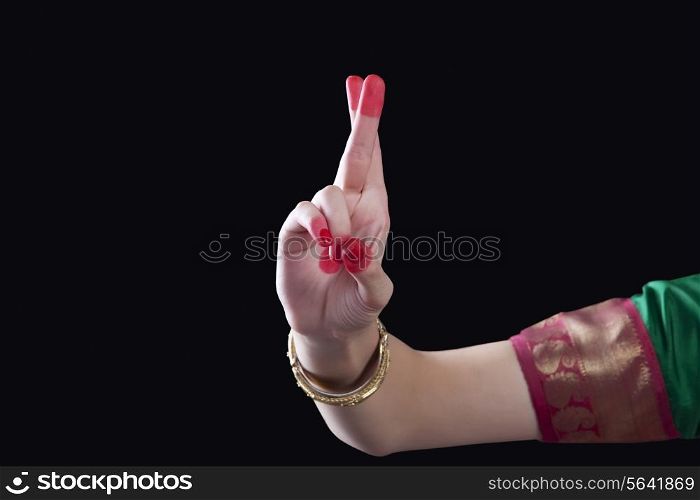 Close-up of a woman&rsquo;s hand making a Bharatanatyam gesture called Kartarimukha on black background