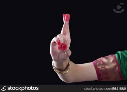Close-up of a woman&rsquo;s hand making a Bharatanatyam gesture called Kartarimukha on black background
