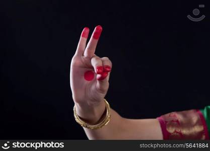Close-up of a woman&rsquo;s hand making a Bharatanatyam gesture called Katakamukha on black background