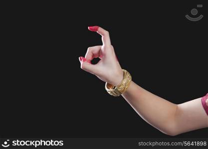 Close-up of a woman&rsquo;s hand making Bharatanatyam gesture called Tamrachuda on black background