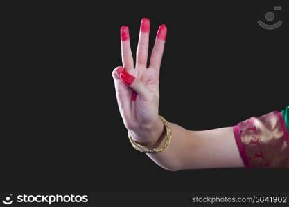Close-up of a woman&rsquo;s hand making Bharatanatyam gesture called Trishula on black background