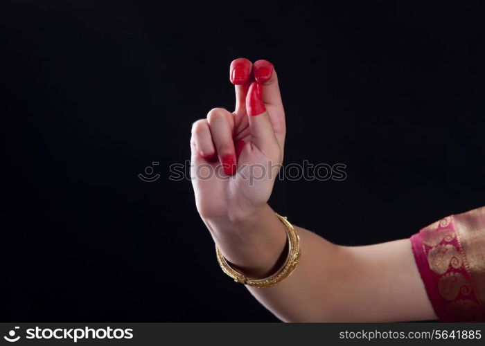 Close-up of a woman&rsquo;s hand making Bharatanatyam gesture on black background