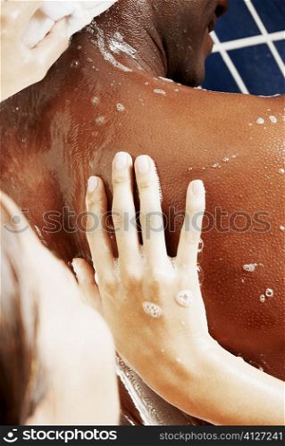Close-up of a woman scrubbing a man&acute;s back