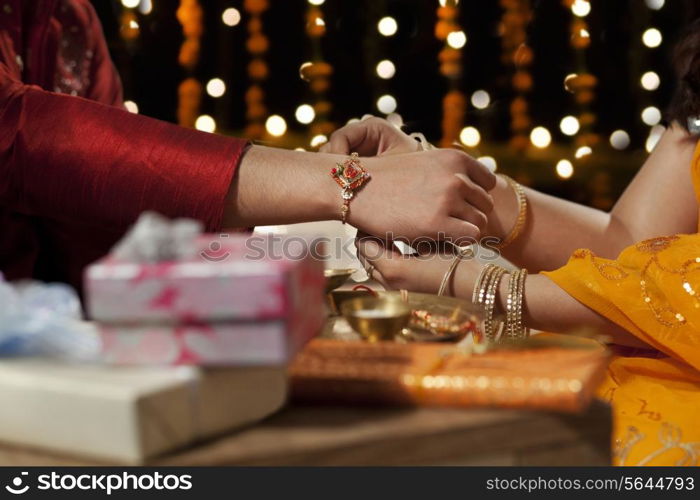 Close-up of a woman tying rakhi on her brother&rsquo;s hand