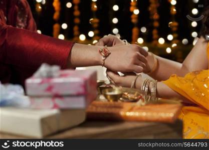 Close-up of a woman tying rakhi on her brother&rsquo;s hand