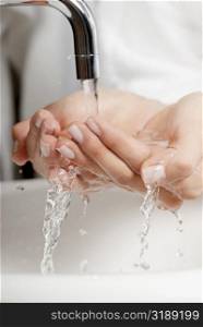 Close-up of a woman washing her hands in the bathroom sink
