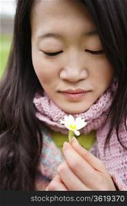 Close-up of a young Asian woman looking at flower