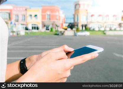 Close up of a young Asian woman using smartphone with a backgrou. Close up of a young Asian woman using smartphone with a background of pastel buildings city and nice blue sky. City lifestyle of young woman on weekend. Outdoor shopping and city lifestyle concept.