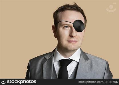 Close-up of a young businessman with eye patch looking away over colored background