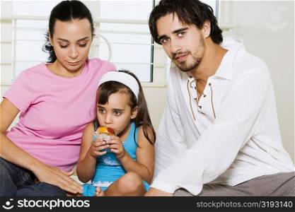 Close-up of a young couple and their daughter eating a pastry