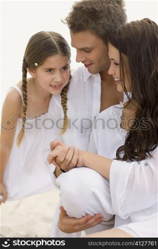 Close-up of a young couple and their daughter on the beach