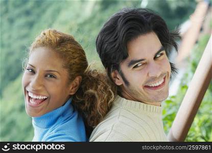 Close-up of a young couple back to back and smiling