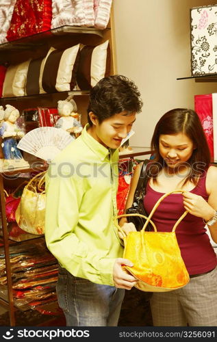 Close-up of a young couple choosing a hand bag in a store