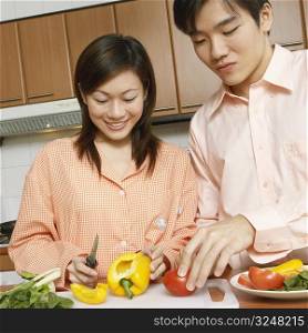 Close-up of a young couple cutting vegetables at a kitchen counter
