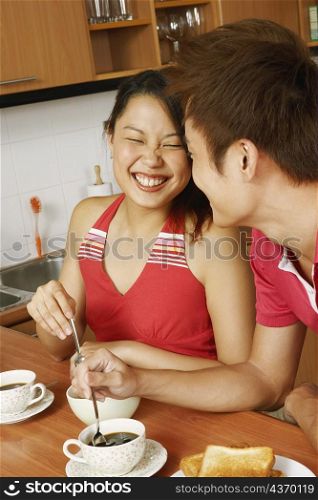 Close-up of a young couple having breakfast and smiling at a kitchen counter