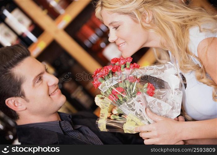 Close-up of a young couple holding a bouquet of flowers and smiling
