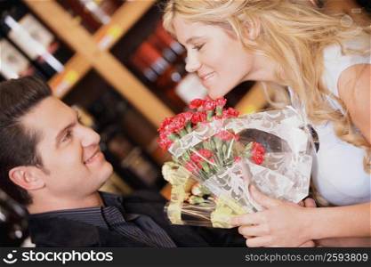 Close-up of a young couple holding a bouquet of flowers and smiling