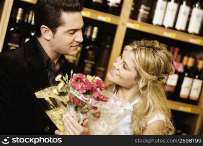 Close-up of a young couple holding a bouquet of flowers in a liquor store