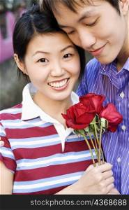 Close-up of a young couple holding a bunch of roses
