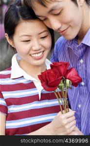 Close-up of a young couple holding a bunch of roses