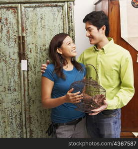 Close-up of a young couple holding a cage and looking at each other