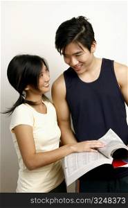 Close-up of a young couple holding a directory and looking at each other