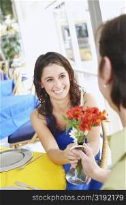 Close-up of a young couple holding a flower vase and smiling in a restaurant