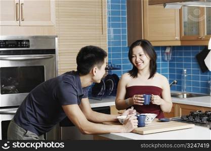 Close-up of a young couple holding cups in the kitchen