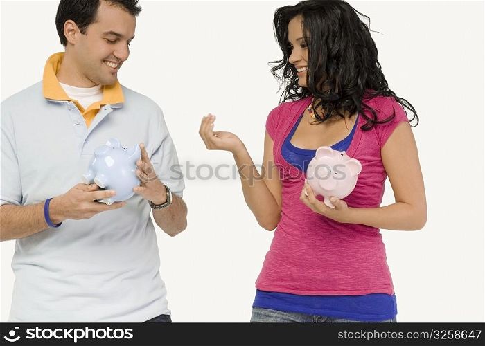Close-up of a young couple holding piggy banks and smiling