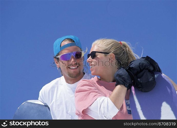 Close-up of a young couple holding snowboards