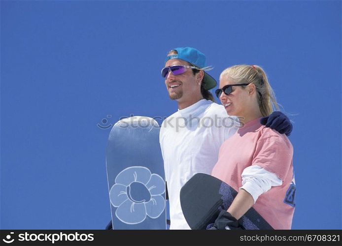 Close-up of a young couple holding snowboards