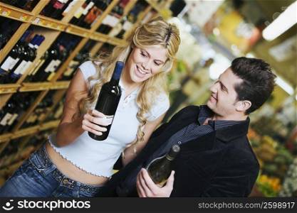 Close-up of a young couple holding wine bottles in a supermarket