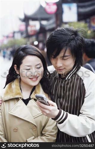 Close-up of a young couple looking at a mobile phone smiling