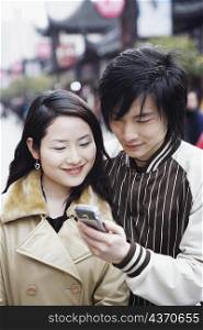 Close-up of a young couple looking at a mobile phone smiling