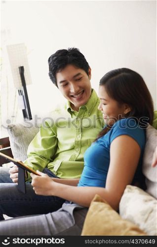 Close-up of a young couple looking at a picture frame and smiling on a couch