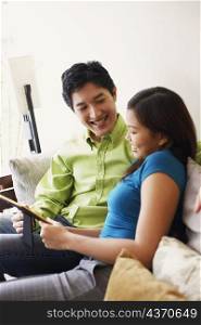 Close-up of a young couple looking at a picture frame and smiling on a couch