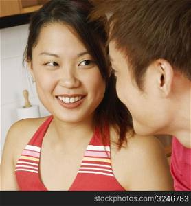 Close-up of a young couple looking at each other at a kitchen counter