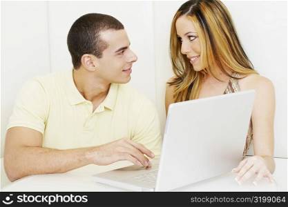 Close-up of a young couple looking at each other in front of a laptop