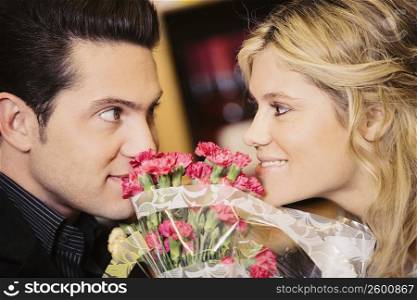 Close-up of a young couple looking at each other with a bouquet of flowers between them