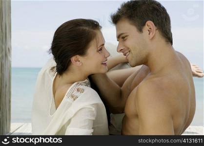 Close-up of a young couple lying on a pier and looking at each other