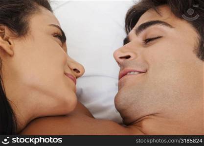Close-up of a young couple lying on the bed looking at each other