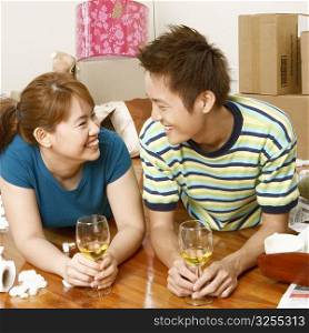 Close-up of a young couple lying on the floor and holding glasses of wine