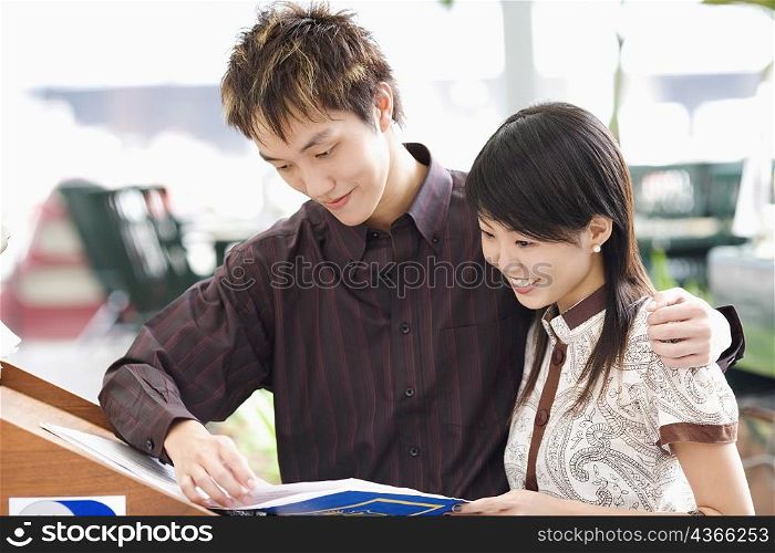 Close-up of a young couple reading a book and smiling