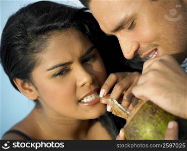 Close-up of a young couple sipping milk from a coconut