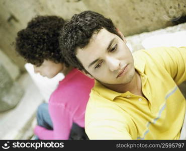 Close-up of a young couple sitting back to back