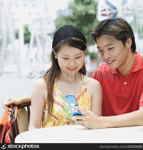 Close-up of a young couple sitting in a cafeteria and looking at mobile phone