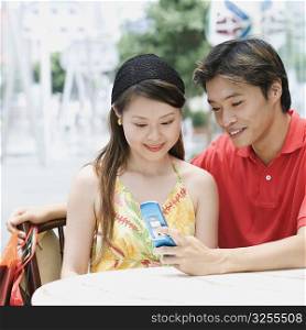 Close-up of a young couple sitting in a cafeteria and looking at mobile phone