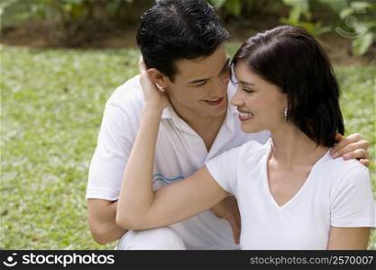 Close-up of a young couple sitting in a garden and smiling