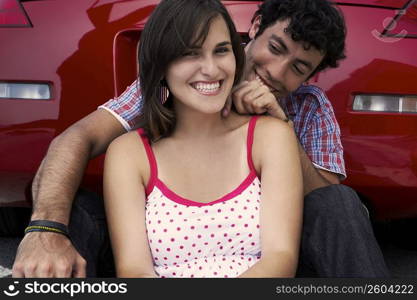 Close-up of a young couple sitting in front of a car